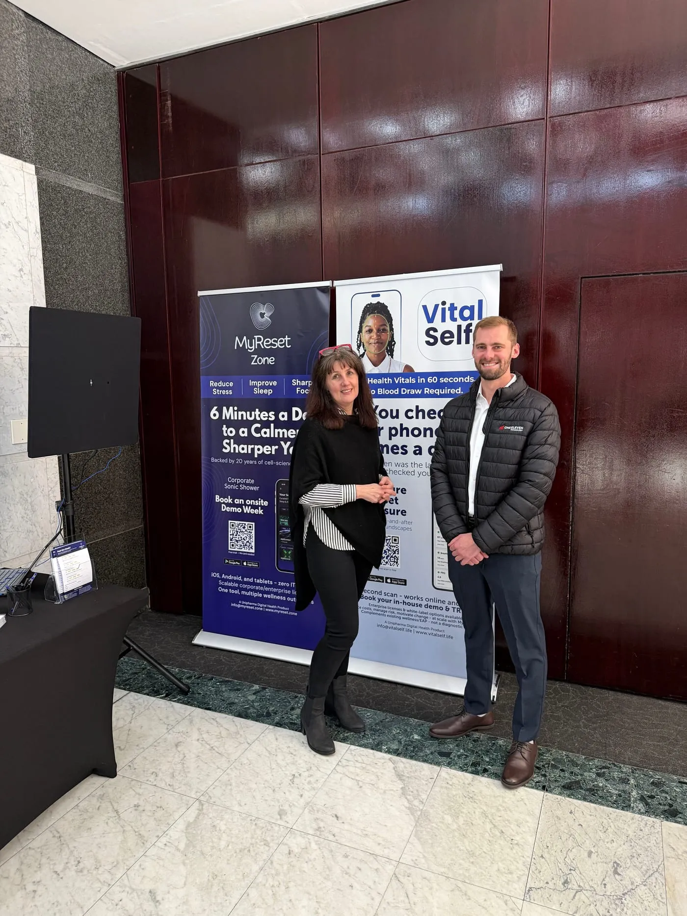 Bridget Hall, founder of MyReset Zone, standing with One Eleven at the MyReset Zone stand in front of the app's banner.